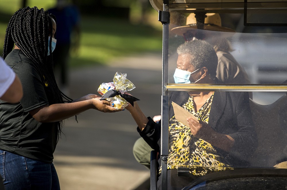 Emery Moore, 14, gives a present to Elizabeth Eckford during her 80th birthday party outside Central High School where students sang Happy Birthday and LeRon McAdoo sang a rendition of Amazing Grace Monday, Oct. 4, 2021, in Little Rock, Ark. Central High became internationally known in 1957 during the desegregation crisis. Eckford and eight other Black students were barred from entering the school by Arkansas National Guard members who had been activated, despite a court-approved desegregation plan. (Stephen Swofford/The Arkansas Democrat-Gazette via AP)