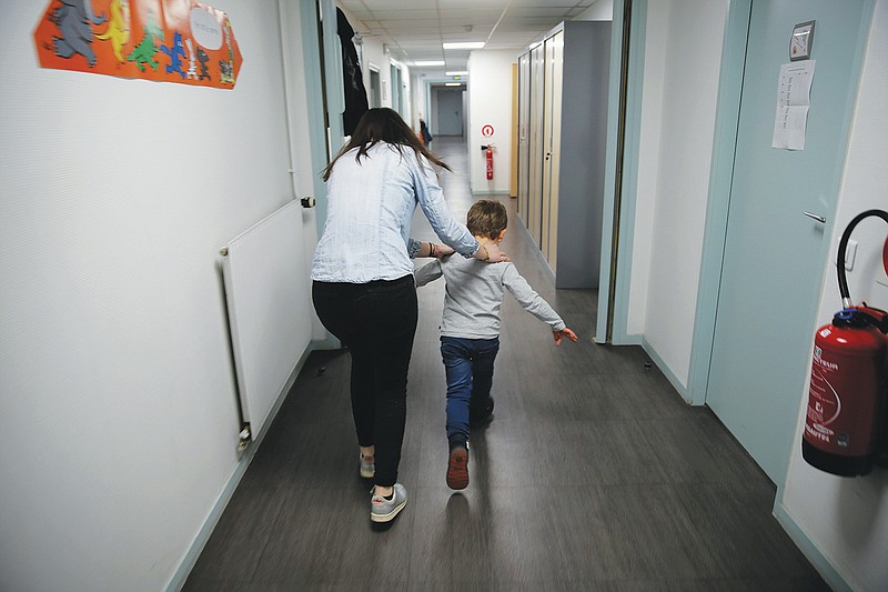 FILE - In this Tuesday, March 2, 2021 file photo, Maelle Allanore, a psychomotor therapist runs down a corridor with a boy in the pediatric unit of the Robert Debre hospital, in Paris, France. The UN's child protection agency is urging governments to pour more money and resources into preserving the mental well-being of children and adolescents. UNICEF, in a report released Tuesday, Oct. 5, sounded alarms about blows to mental health from the COVID-19 pandemic that have hit poor and vulnerable children particularly hard. (AP Photo/Christophe Ena, File)