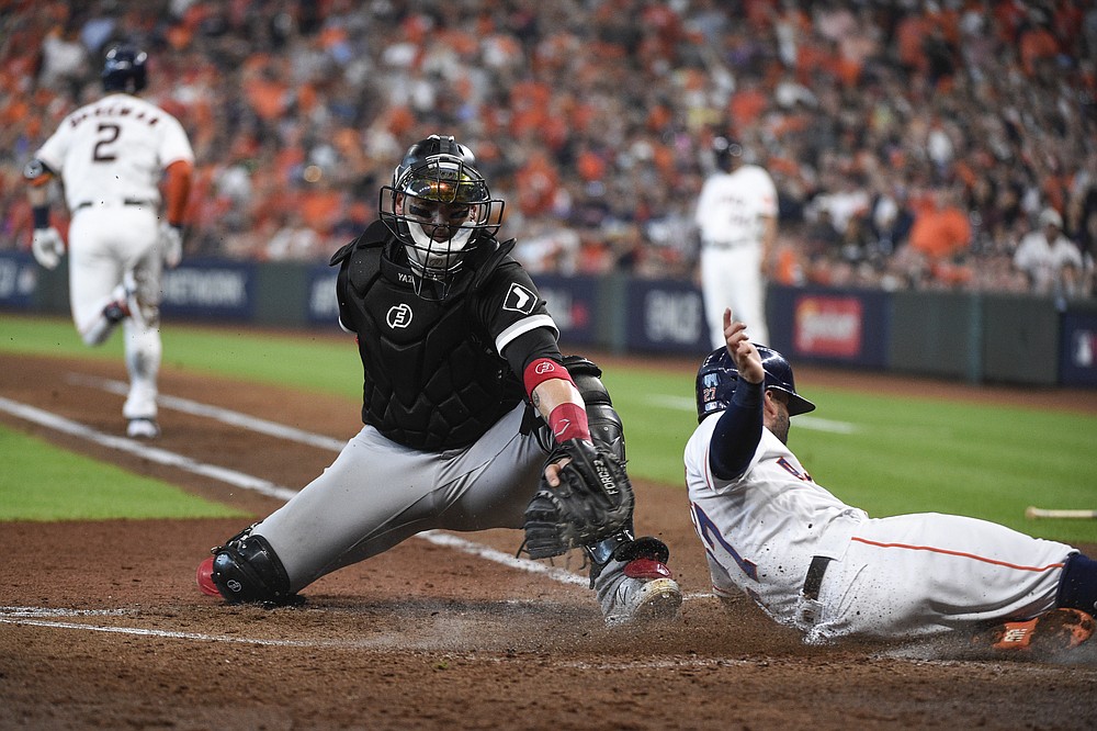 Houston Astros' Jose Altuve, right, slides at home plate while scoring ahead of the tag by Chicago White Sox catcher Yasmani Grandal, center, on a fielder's choice ground ball by Alex Bregman (2) during the third inning in Game 1 of a baseball American League Division Series Thursday, Oct. 7, 2021, in Houston. (AP Photo/Eric Christian Smith)