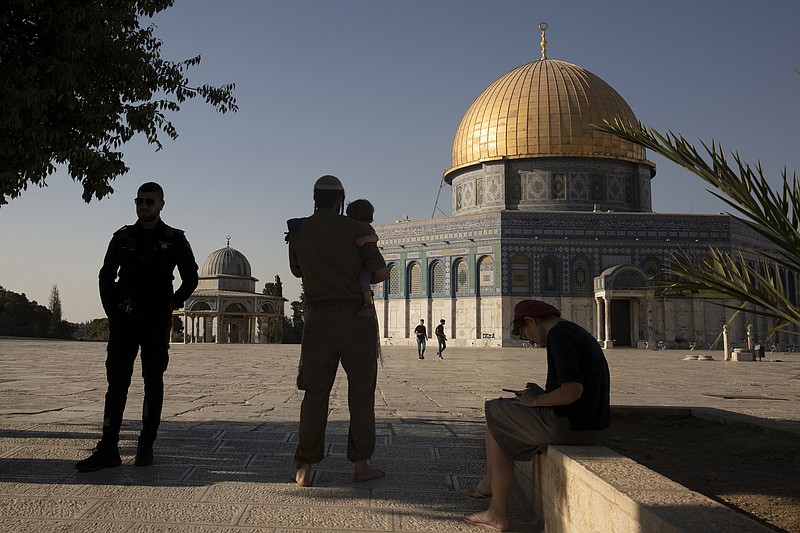 An Israeli police officer stands guard as a religious Jew in Army uniform visits the Temple Mount, known to Muslims as the Noble Sanctuary, on the Al-Aqsa Mosque compound in the Old City of Jerusalem, Tuesday, Aug. 3, 2021. A ruling by a local Israeli court in favor of a Jewish man who prayed quietly at a flashpoint Jerusalem holy site has angered Muslim authorities, who denounced it on Thursday, Oct. 7, 2021 as a violation of the fragile status quo governing the compound. (AP Photo/Maya Alleruzzo, file)