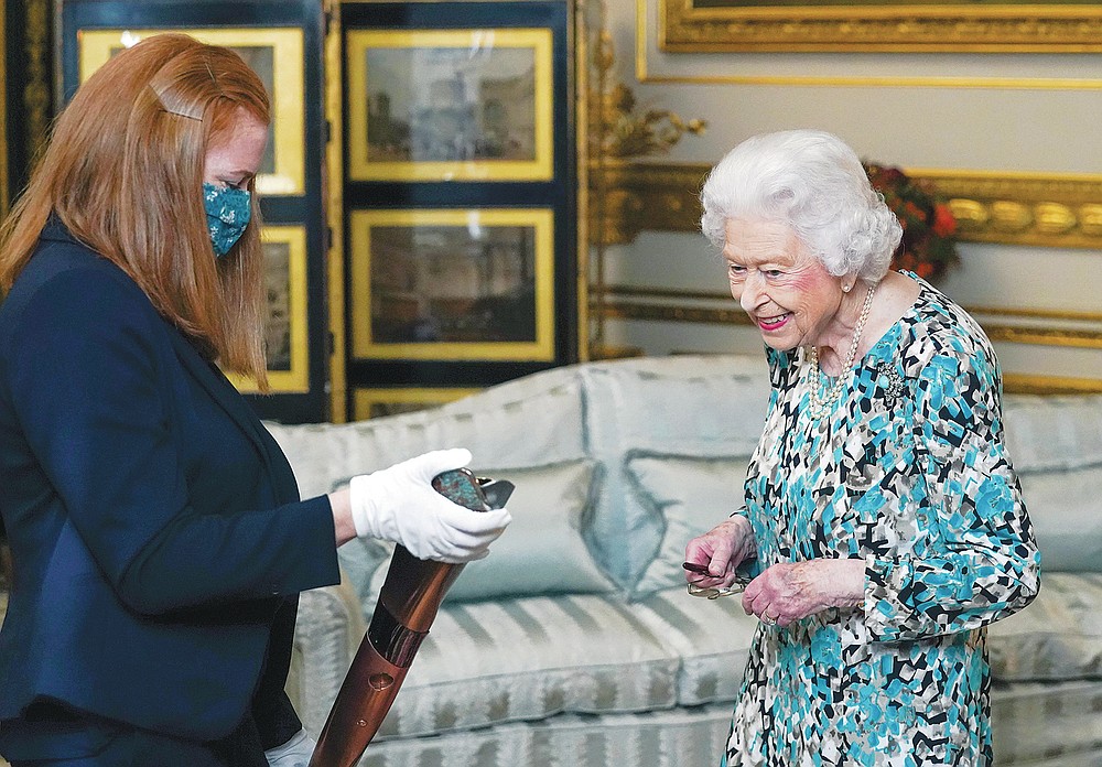 Britain's Queen Elizabeth II looks at the Birmingham 2022 Commonwealth Games Baton that will carry a message from her during a relay which starts at Buckingham Palace before 7,500 bearers take the baton on a 90,000-mile journey to all 72 nations and territories of the Commonwealth over 294 days, in Windsor, England, Monday, Oct. 4, 2021. (Steve Parsons/Pool Photo via AP)