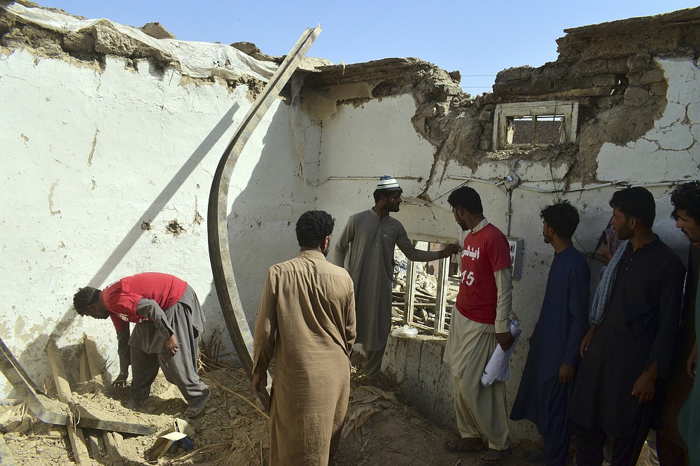 Members of a family and volunteers take belongings from a damaged house following an earthquake in Harnai, about 100 kilometers (60 miles) east of Quetta, Pakistan, Thursday, Oct. 7, 2021. The powerful earthquake collapsed at least one coal mine and dozens of mud houses in southwest Pakistan early Thursday. (AP Photo/Arshad Butt)