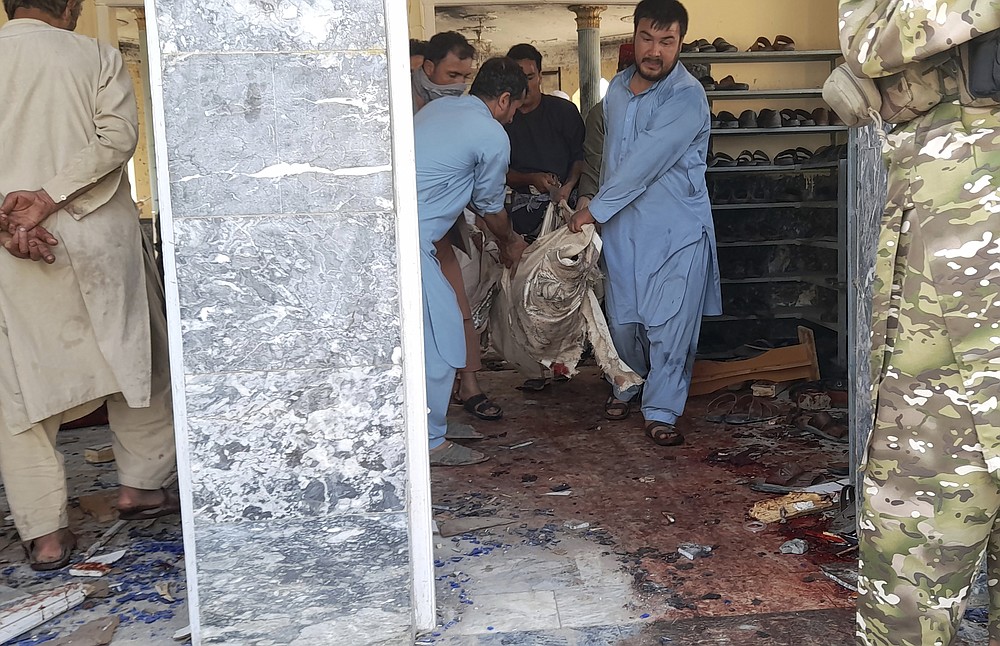 People carry the body of a victim following a bombing in Kunduz province, northern Afghanistan, Friday, Oct. 8, 2021. A powerful explosion in a mosque frequented by a Muslim religious minority in northern Afghanistan on Friday has left several casualties, witnesses and the Taliban's spokesman said. (AP Photo/Abdullah Sahil)