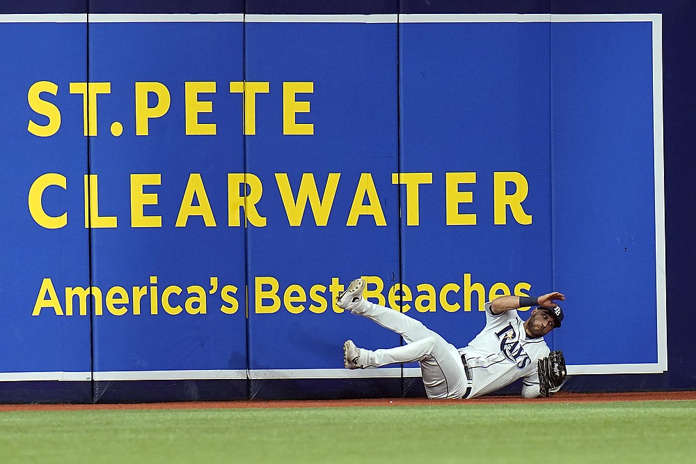 Tampa Bay Rays center fielder Kevin Kiermaier falls to the track after making a catch in the third inning of a fly ball hit by Boston Red Sox's Rafael Devers in Game 2 of a baseball American League Division Series, Friday, Oct. 8, 2021, in St. Petersburg, Fla. (AP Photo/Chris O'Meara)