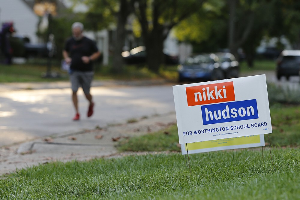 A person jogs past a school board yard sign Thursday, Oct. 7, 2021, in Worthington, Ohio. Across Ohio and the nation, parental protests over social issues like mask mandates, gender-neutral bathrooms, teachings on racial history, sexuality and mental and emotional health are being leveraged into school board takeover campaigns. (AP Photo/Jay LaPrete)
