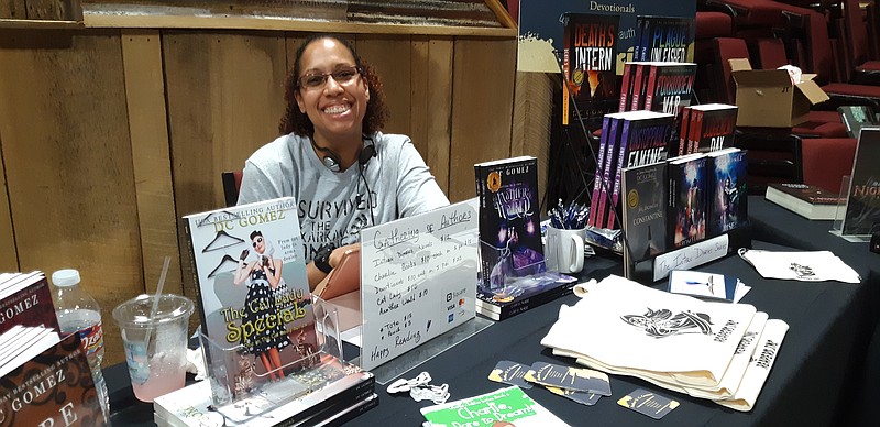 Local author D.C. Gomez shows off her books on Saturday at Gathering of Authors. Gomez still attends as a fan, meeting other authors and sharing the love of books and storytelling.Staff photo by Junius Stone