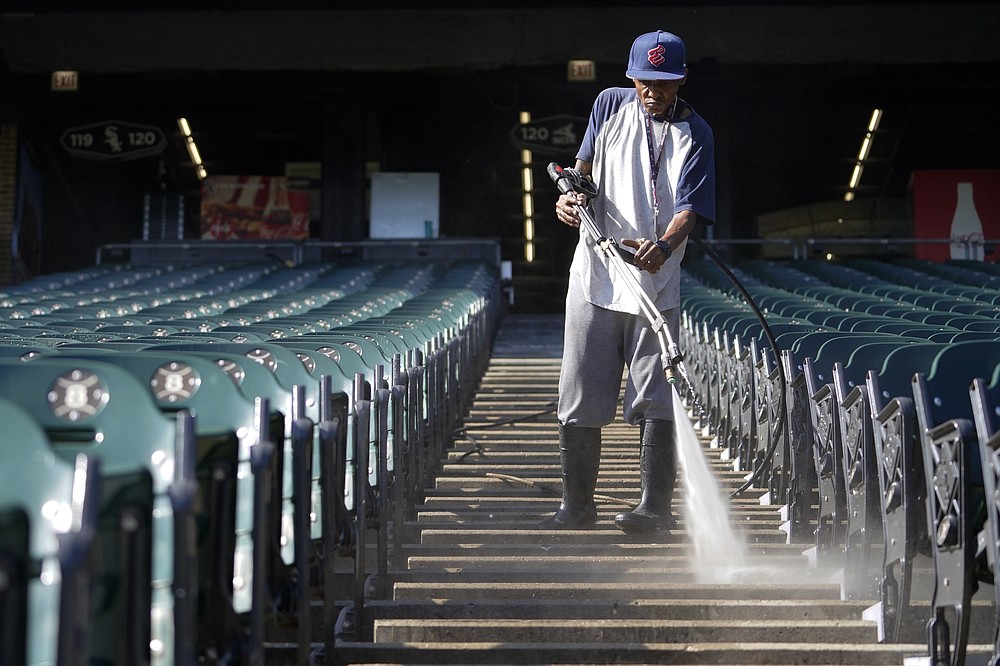 A stadium worker cleans the seating area during baseball practice for the American League Division Series, Saturday, Oct. 9, 2021, in Chicago. The Chicago White Sox host the Astros in Game 3 on Sunday. (AP Photo/Nam Y. Huh)
