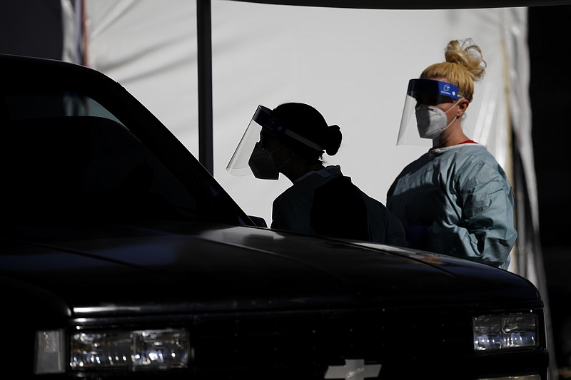 FILE - In this July 10, 2020, file photo, healthcare workers test patients in their cars at a drive-thru coronavirus testing site run by the University of Nevada Las Vegas School of Medicine and the Nevada National Guard in Las Vegas. Nevada this week became one of the last states to include rapid antigen tests in its coronavirus tallies. Experts say the change could provide a fuller picture of the pandemic but also upend metrics used to gauge how the virus is spreading. Health officials say they weren't added earlier because their limited resources and staff had focused on vaccines and contact tracing confirmed cases.(AP Photo/John Locher, File)