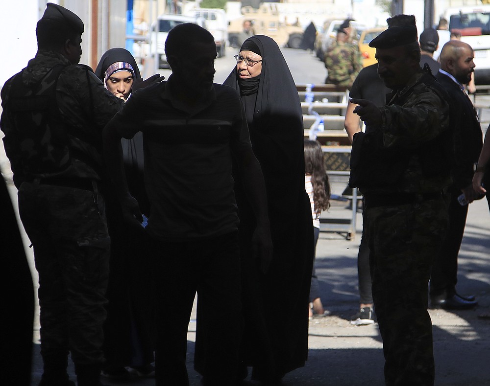 Security forces stand guard outside a polling center duringin the country's parliamentary elections in Baghdad, Iraq, Sunday, Oct. 10, 2021. Iraq closed its airspace and land border crossings on Sunday as voters headed to the polls to elect a parliament that many hope will deliver much needed reforms after decades of conflict and mismanagement. (AP Photo/Hadi Mizban)