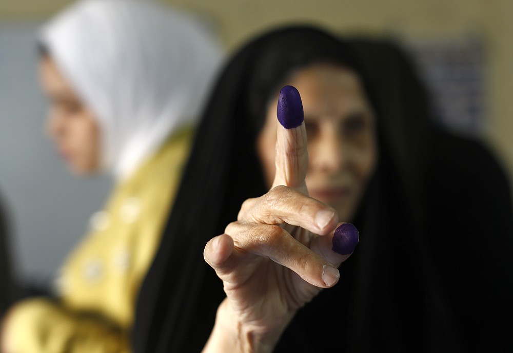 An Iraqi elderly woman shows her ink-stained finger after casting her vote inside a polling station in the country's parliamentary elections in Baghdad, Iraq, Sunday, Oct. 10, 2021. Iraq closed its airspace and land border crossings on Sunday as voters headed to the polls to elect a parliament that many hope will deliver much needed reforms after decades of conflict and mismanagement. (AP Photo/Hadi Mizban)
