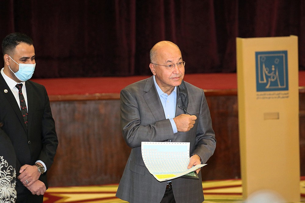 Iraqi President Barham Salih, center, casts his vote during the parliamentary elections in Baghdad, Iraq, Sunday, Oct. 10, 2021. Iraq closed its airspace and land border crossings on Sunday as voters headed to the polls to elect a parliament that many hope will deliver much needed reforms after decades of conflict and mismanagement. (AP Photo/Khalid Mohammed)