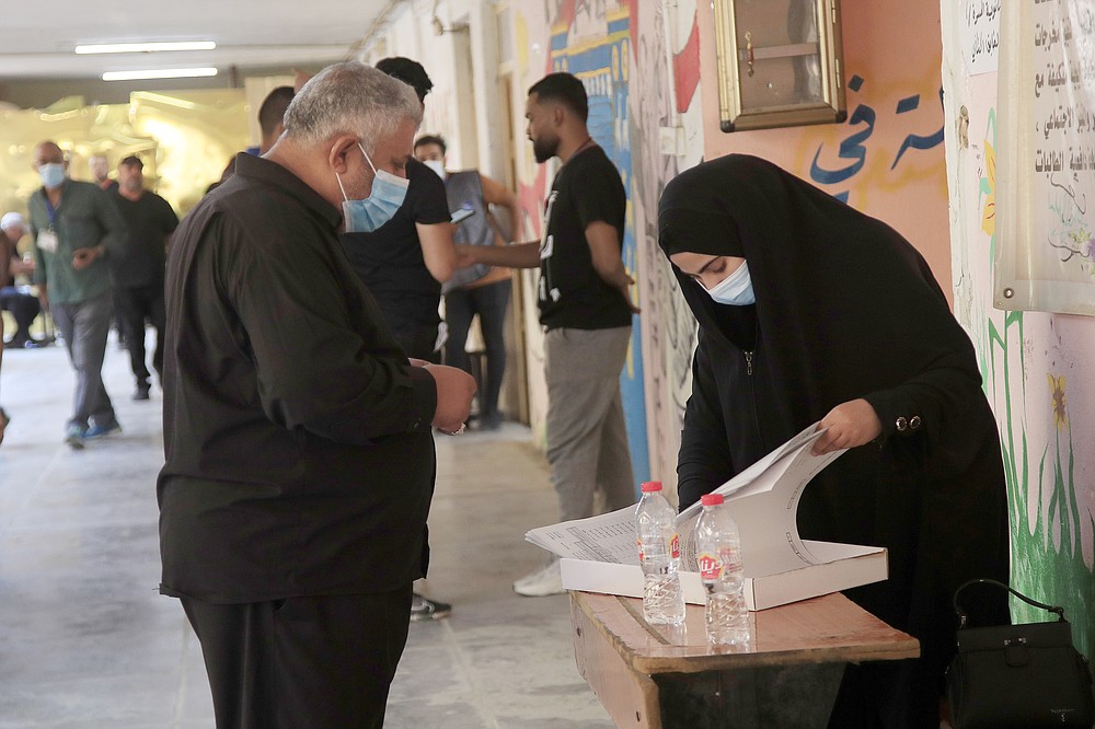 Iraqis voters gather to cast their vote at a ballot station in the country's parliamentary elections in Baghdad, Iraq, Sunday, Oct. 10, 2021. Iraq closed its airspace and land border crossings on Sunday as voters headed to the polls to elect a parliament that many hope will deliver much needed reforms after decades of conflict and mismanagement.. (AP Photo/Hadi Mizban)