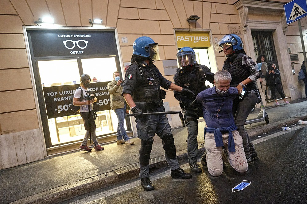 A demonstrator is apprehended by police officers after clashes during a protest, in Rome, Saturday, Oct. 9, 2021. Thousands of demonstrators protested Saturday in Rome against the COVID-19 health pass that Italian workers, both the public and private sectors, must display to access their workplaces from Oct. 15 under a government decree. (Mauro Scrobogna/LaPresse via AP)