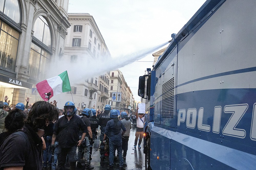 Demonstrators are sprayed by police water cannon as clashes occur during a protest, in Rome, Saturday, Oct. 9, 2021. Thousands of demonstrators protested Saturday in Rome against the COVID-19 health pass that Italian workers, both the public and private sectors, must display to access their workplaces from Oct. 15 under a government decree. (Mauro Scrobogna/LaPresse via AP)