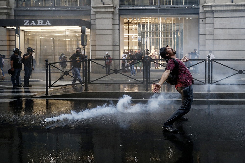 A demonstrator reacts as police fire teargas during a protest, in Rome, Saturday, Oct. 9, 2021. Thousands of demonstrators protested Saturday in Rome against the COVID-19 health pass that Italian workers, both the public and private sectors, must display to access their workplaces from Oct. 15 under a government decree. (Cecilia Fabiano/LaPresse via AP)
