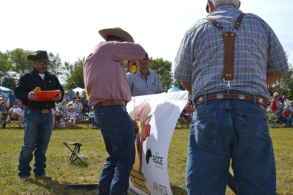 Announcer Jeremy Weir of Siloam Springs, left, watches to see how high the jump will be that Harold and Don Shockley are raising as judge Allen McBurnett measures at the 32nd annual Pea Ridge Mule Jump.