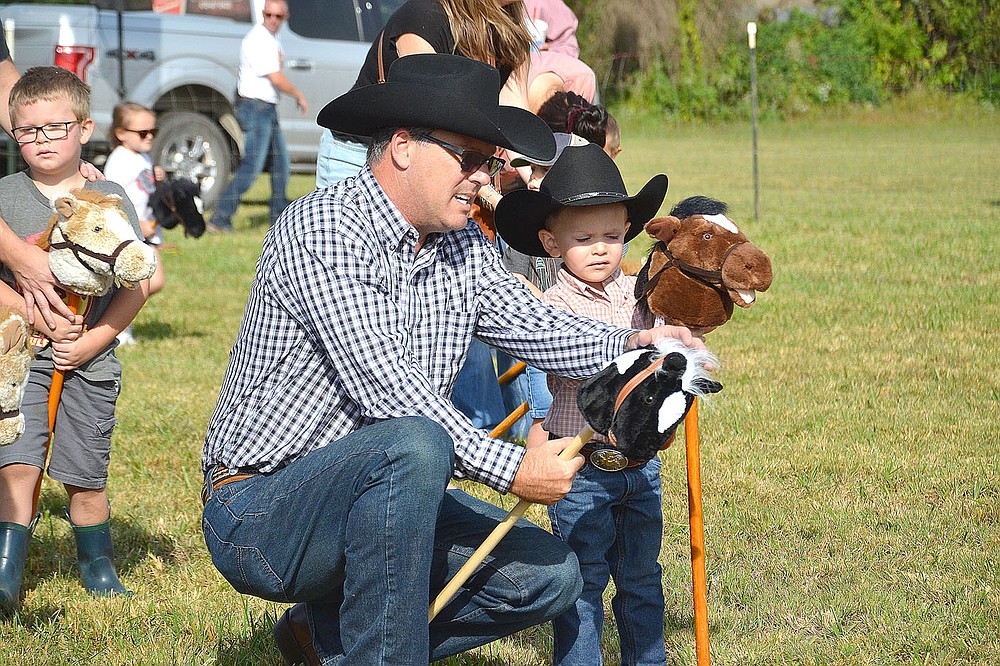 David McCord of Lowell, helped his grandson Joseph Tattoo, 3, with the stick mule race Saturday at the 32nd annual Pea Ridge Mule Jump.