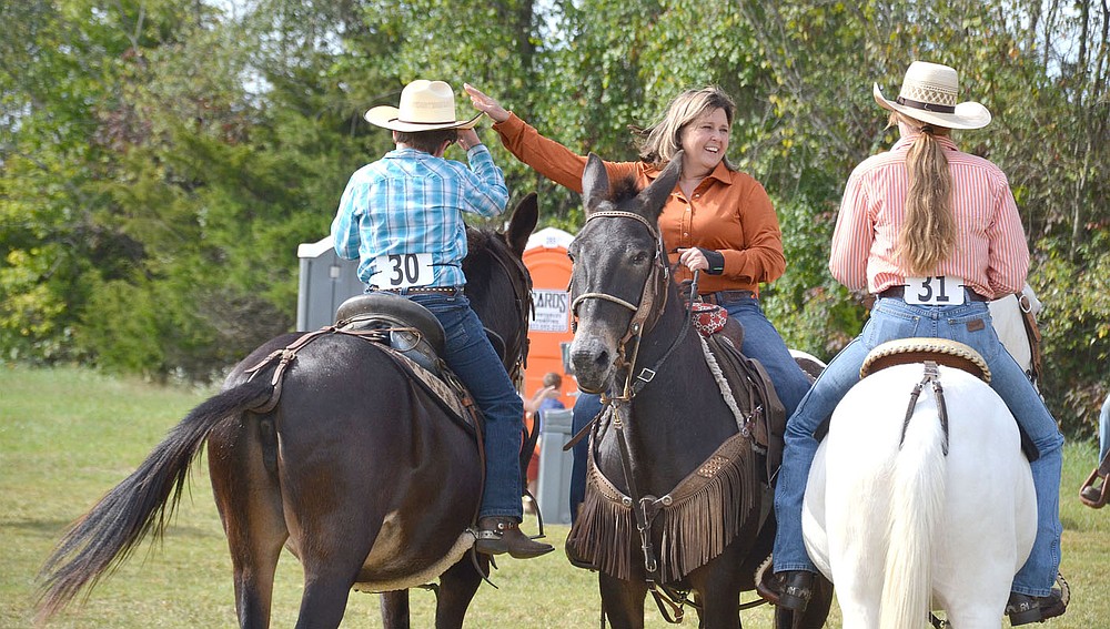 Becki Sams, whose father Joe Sams was a long-time competitor at the mule jump, visits with fellow mule riders Saturday while waiting her turn for the arena.
