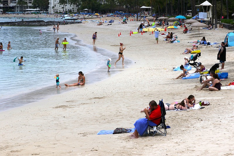 FILE — In this Aug. 24, 2021, file photo people sit on a Waikiki Beach in Honolulu. Hawaii officials are facing pressure to increase covid-19 testing for travelers. The islands are weathering a record surge and federal guidelines are being changed to require negative virus tests from both vaccinated and unvaccinated travelers to the U.S. (AP/Caleb Jones, File)