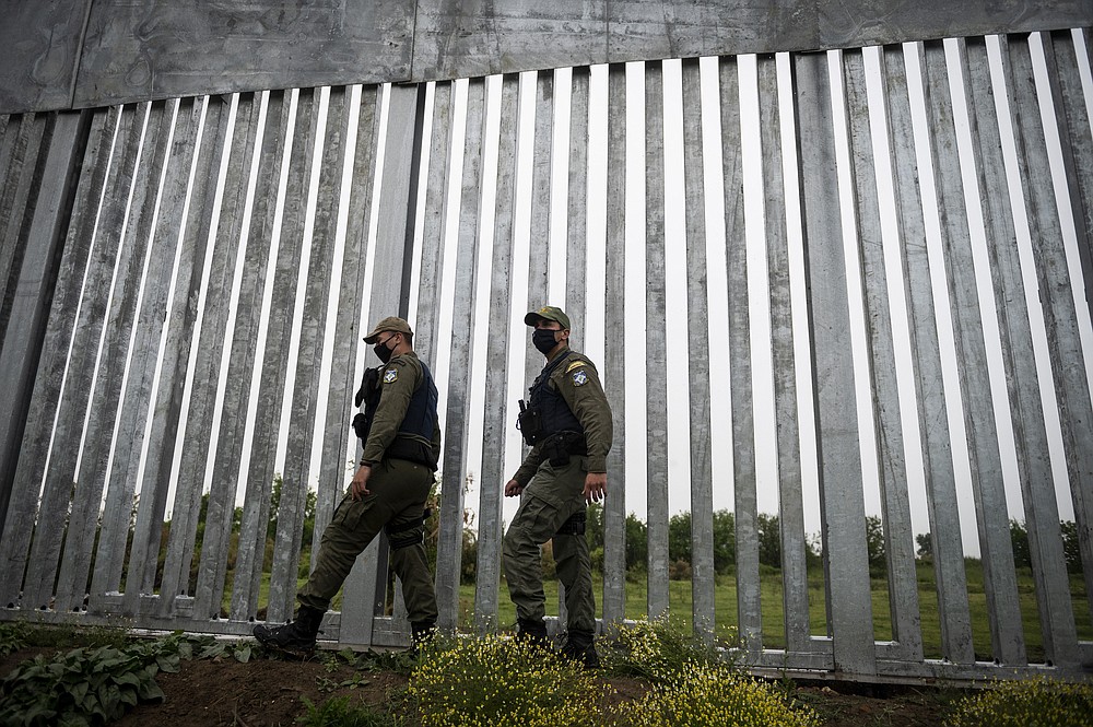 FILE - In this Friday, May 21, 2021 file photo, police officers patrol alongside a steel wall at Evros river, near the village of Poros, at the Greek - Turkish border, Greece. Greece will further increase a border guard at its frontier with Turkey, fearing an upcoming spike in attempted illegal migration, officials said Monday, Oct. 11, 2021. (AP Photo/Giannis Papanikos, File)
