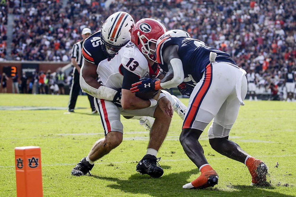 Georgia quarterback Stetson Bennett (13) is tackled by Auburn defensive end Caleb Johnson (45) and safety Smoke Monday (21) during the first half of an NCAA college football game Saturday, Oct. 9, 2021 in Auburn, Ala. Monday was called for targeting and was ejected from the game . (AP Photo/Butch Dill)
