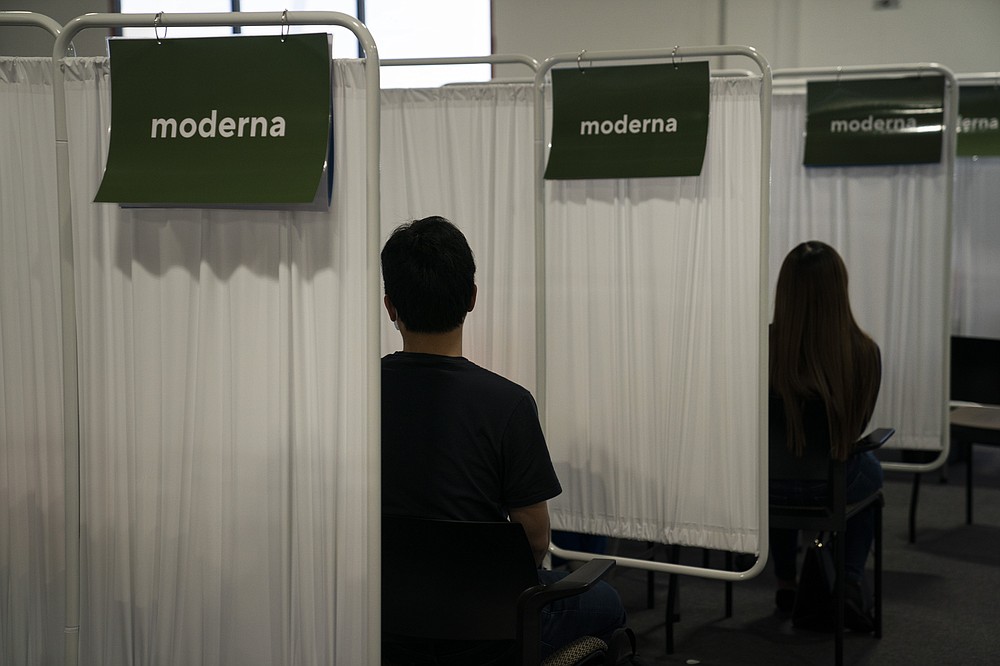 FILE - In this May 21, 2021, file photo, two people wait to receive the Moderna COVID-19 vaccine at Providence Edwards Lifesciences vaccination site in Santa Ana, Calif. Starting Thursday, Oct. 14, 2021, the Food and Drug Administration convenes its independent advisers for the first stage in the process of deciding whether extra shots of Moderna or Johnson & Johnson vaccines should be dispensed and, if so, who should get them and when. (AP Photo/Jae C. Hong, File)