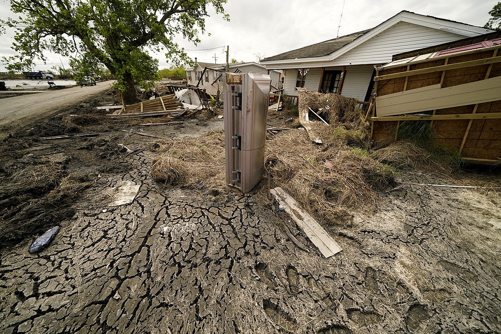 A casket that floated from its tombs during flooding from Hurricane Ida sits in a lawn of a destroyed home in Ironton, La., Monday, Sept. 27, 2021. Hurricane Ida swept through Louisiana with furious winds that ripped roofs off buildings and storm surge so powerful it moved homes. And what it wrought on the living it also wrought on the dead, moving vaults and caskets and adding another layer of trauma on families and communities recovering from the powerful storm. (AP Photo/Gerald Herbert)