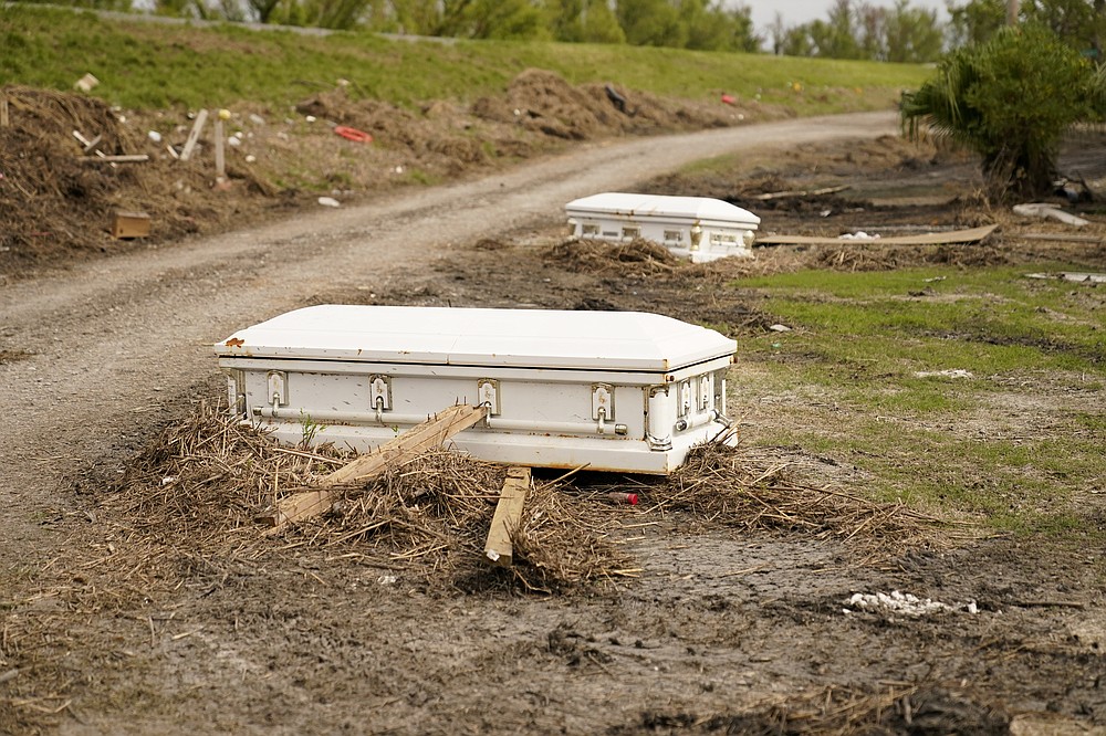 Caskets that floated from their tombs during flooding from Hurricane Ida, sit along a roadside in Ironton, La., Monday, Sept. 27, 2021. Hurricane Ida swept through Louisiana with furious winds that ripped roofs off buildings and storm surge so powerful it moved homes. And what it wrought on the living it also wrought on the dead, moving vaults and caskets and adding another layer of trauma on families and communities recovering from the powerful storm. (AP Photo/Gerald Herbert)