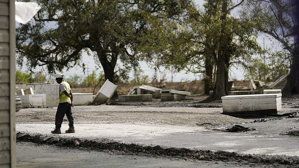 A worker walks through a heavily damaged cemetery in Ironton, La., Monday, Sept. 27, 2021. A Louisiana task force is working to gather vaults and caskets disrupted from their burial sites by Hurricane Ida and rebury them. (AP Photo/Gerald Herbert)