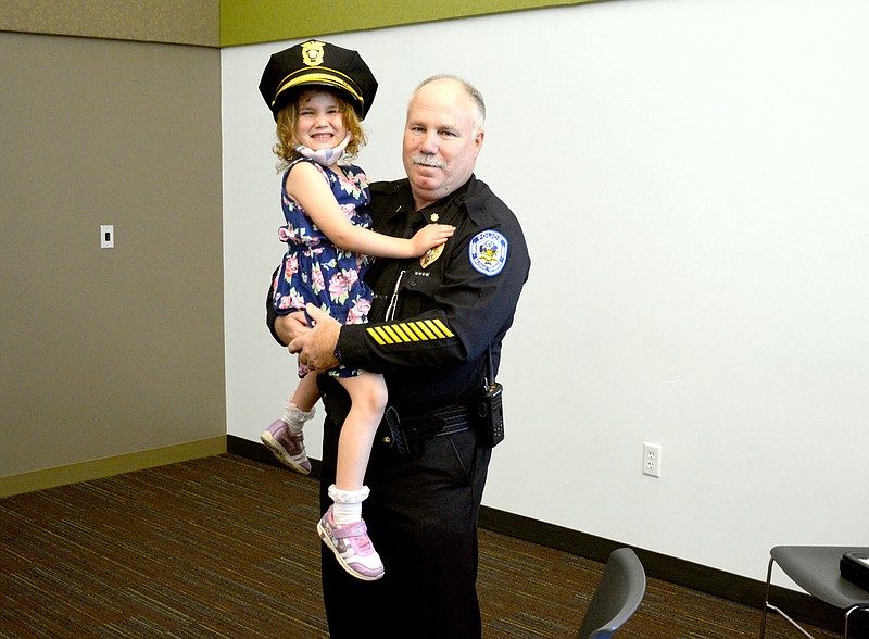 Marc Hayot/Herald-Leader Retired Deputy Chief Major Geoff Lewis (right), poses with his granddaughter Briar Florez at Lewis' retirement party on Friday at the library. Lewis served 39 years in law enforcement and 14.5 years with the Siloam Springs Police Department.