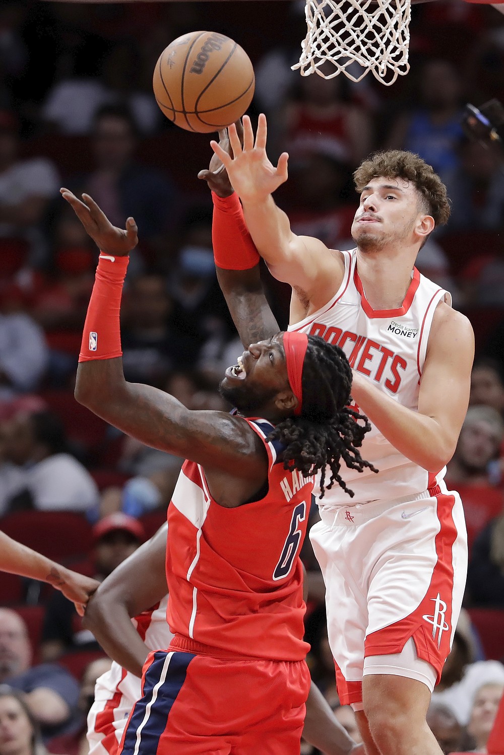 Houston Rockets center Alperen Sengun, top, tries to knock away a rebound from Washington Wizards center Montrezl Harrell (6) during the second half of an NBA preseason basketball game Tuesday, Oct. 5, 2021, in Houston. (AP Photo/Michael Wyke)