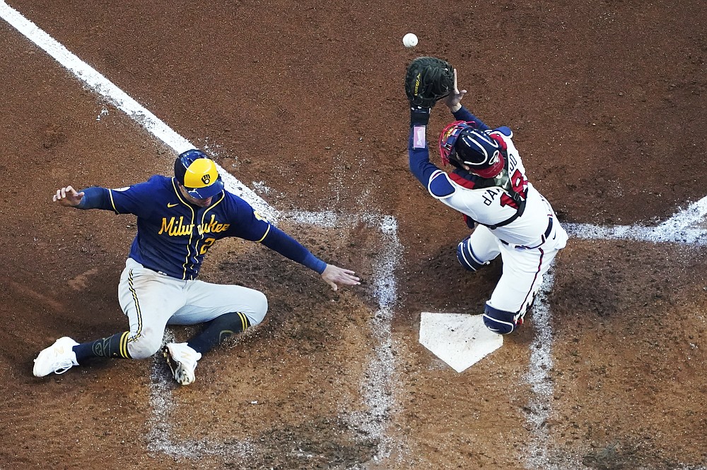 Milwaukee Brewers' Avisail Garcia (24) slides in to home as Atlanta Braves catcher Travis d'Arnaud (16) misses the tag during the fourth inning of Game 4 of a baseball National League Division Series, Tuesday, Oct. 12, 2021, in Atlanta. (AP Photo/John Bazemore)