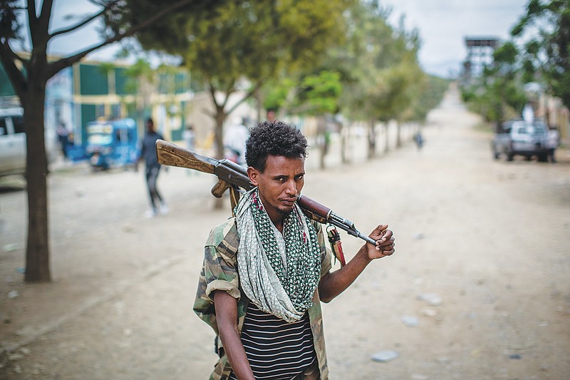 FILE - In this Friday, May 7, 2021 file photo, a fighter loyal to the Tigray People's Liberation Front (TPLF) walks along a street in the town of Hawzen, then-controlled by the group but later re-taken by government forces, in the Tigray region of northern Ethiopia. Tigray forces say Ethiopia&#x2019;s government has launched its threatened major military offensive against them in an attempt to end a nearly year-old war. A statement from the Tigray external affairs office on Monday, Oct. 11 alleged that hundreds of thousands of Ethiopian &#x201c;regular and irregular fighters&#x201d; launched a coordinated assault on several fronts. (AP Photo/Ben Curtis, File)