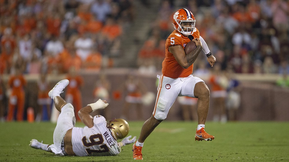 Clemson's Trevor Lawrence (16) hands the ball off to Travis Etienne (9)  during the first half of an NCAA college football game against North  Carolina State in Raleigh, N.C., Saturday, Nov. 9