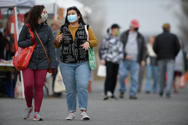 Patrons walk April 3, 2021, while visiting the Fayetteville Farmers Market at the downtown square. The city's Board of Health on Wednesday considered conditions to recommend lifting the city's mask mandate for all public spaces. (File photo/NWA Democrat-Gazette/Andy Shupe)