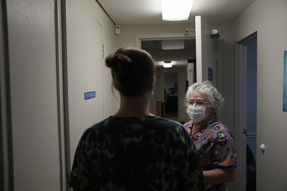 A 25-year-old woman from Texarkana, Texas, whose husband and nursing toddler waited outside in their car, is guided by lab technician Stephannie Chaffee as she goes to meet with a doctor to be given pills and guidance for a medical abortion, Saturday, Oct. 9, 2021, at Hope Medical Group for Women in Shreveport, La. The nation's most restrictive abortion law is driving many women from Texas to seek services in neighboring states. The woman said she was already five weeks along before she realized she was pregnant, and she knew it would be impossible to schedule the required two visits at a Texas clinic. (AP Photo/Rebecca Blackwell)