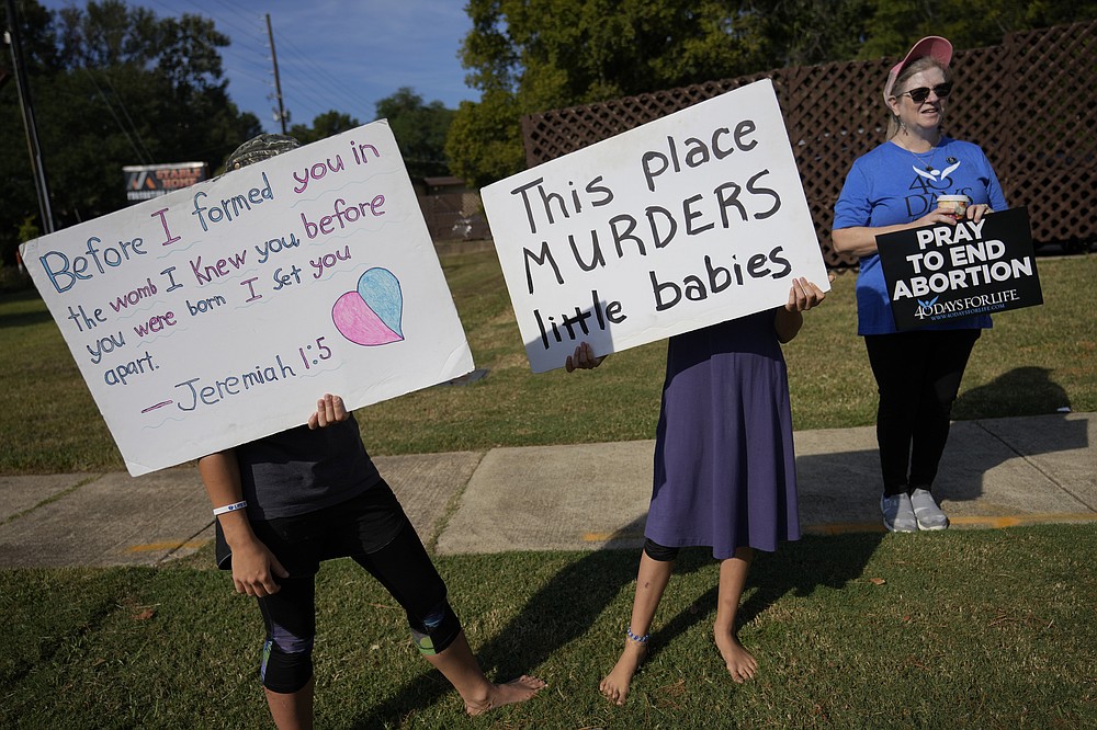 Anti-abortion protesters, including two adolescent girls, hold signs as they stand outside Hope Medical Group for Women, Saturday, Oct. 9, 2021, in Shreveport, La. As most of the women entered the clinic's parking lot, they were met by two groups of anti-abortion protesters, mostly men from East Texas who regularly make the trip to Shreveport. (AP Photo/Rebecca Blackwell)