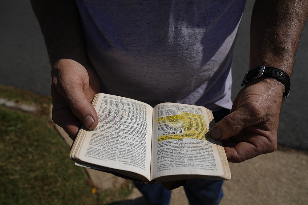 John Powers, 44, from Jacksonville, Texas, quietly reads a passage from a bible brought by a fellow anti-abortion protester, outside Hope Medical Group for Women, Saturday, Oct. 9, 2021, in Shreveport, La. Powers said he typically makes the nearly two-hour drive twice a month with the goal of getting any woman to change her mind. In the 13 years he's been protesting outside of clinics, he says he's successfully convinced two women not to go through with their abortions, which he calls "turnarounds." (AP Photo/Rebecca Blackwell)