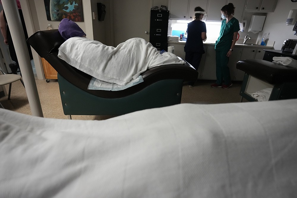 A woman naps, bundled up against the air conditioning, as she waits to have an abortion, Saturday, Oct. 9, 2021, at Hope Medical Group for Women in Shreveport, La. The nation's most restrictive abortion law is driving many women from Texas to seek services in neighboring states. The abortion clinic in Shreveport, is among the clinics being inundated. (AP Photo/Rebecca Blackwell)