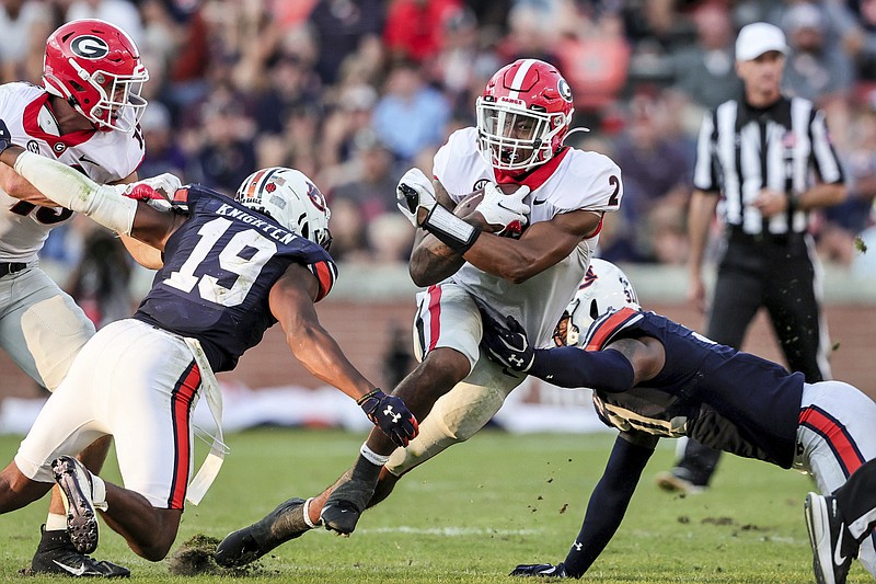 Georgia running back Kendall Milton (2) carries the ball as he splits Auburn safety Bydarrius Knighten (19) and linebacker Chandler Wooten (31) during the second half of an NCAA college football game Saturday, Oct. 9, 2021, in Auburn, Ala. (AP Photo/Butch Dill)