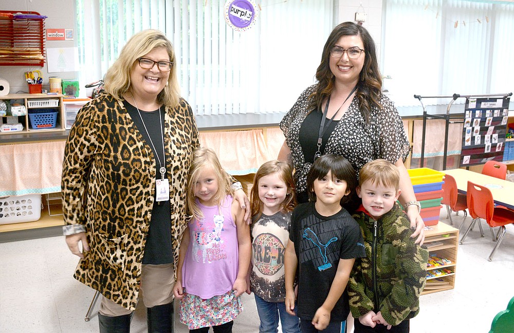 Marc Hayot/Siloam Sunday Northside Elementary Pre-K teachers Angela Veltmann (left) and Elizabeth McRee pose with their students on Thursday as members of the Siloam Springs school board visited Northside, had lunch, then toured the renovations made to the campus.