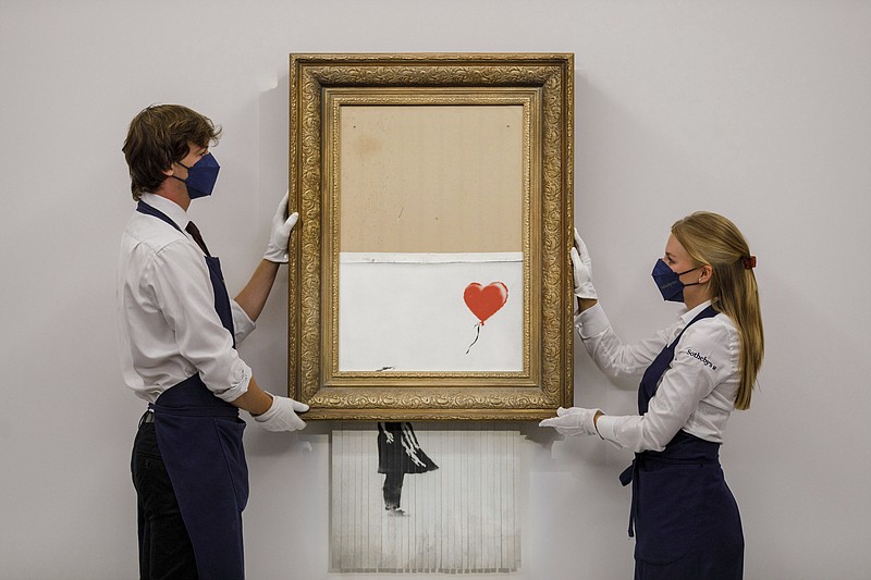 In this handout photo provided by Sotheby's Auction House, the auction for Banksy's &quot;Love is the Bin&quot; takes place in London, Thursday, Oct. 14, 2021. A work by British street artist Banksy that sensationally self-shredded just after it sold for $1.4 million has sold again for $25.4 million at an auction on Thursday. &#x201c;Love is in the Bin&#x201d; was offered by Sotheby&#x2019;s in London, with a presale estimate of $5.5 million to $8.2 million. (Sotheby's Auction House via AP)