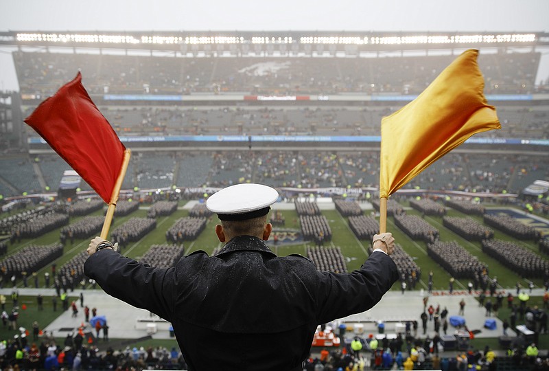 FILE - A Navy Midshipman signals his classmate on the field ahead of an NCAA college football game against Army in Philadelphia, in this Saturday, Dec. 14, 2019, file photo. Bump Army-Navy or go head-to-head with NFL? That's the choice facing those in charge with expanding the College Football Playoff if they want to take the format from four to 12 teams  (AP Photo/Matt Rourke, File)