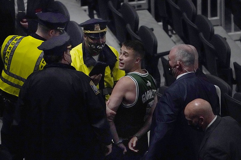 FILE - A fan is handcuffed and escorted out of TD Garden by police after allegedly throwing a water bottle at Brooklyn Nets' Kyrie Irving as Irving left the court after Game 4 of an NBA basketball first-round playoff series in Boston, in this Sunday, May 30, 2021, file photo. Mindful of high-profile incidents of unruly fan behavior in recent years, the NBA has partnered with the National District Attorneys Association to connect franchises with prosecutors who can serve as points of contact with teams when misconduct occurs. (AP Photo/Elise Amendola, File)