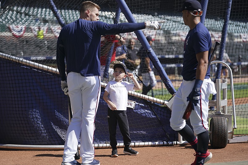 Atlanta Braves' Freddie Freeman, left, works out with his child Charlie Freeman, center, during a workout ahead of baseballs National League Championship Series against the Los Angeles Dodgers, Friday, Oct. 15, 2021, in Atlanta. (AP Photo/Brynn Anderson)