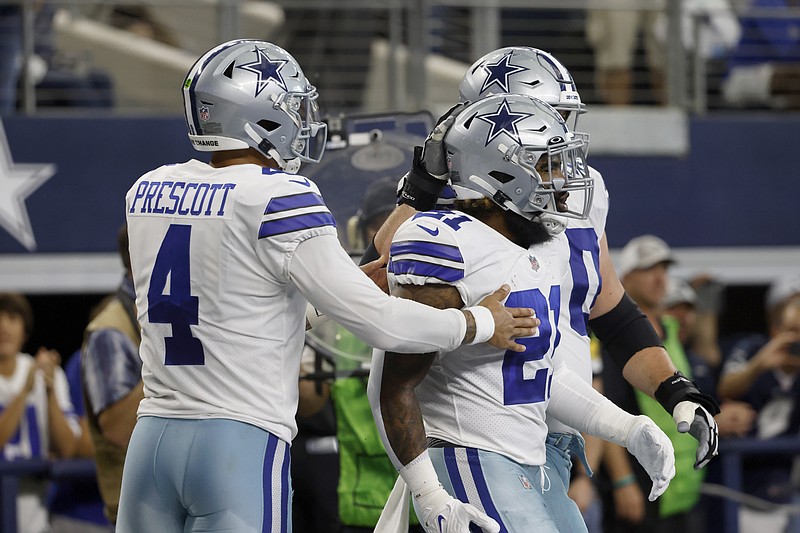 Dallas Cowboys' Dak Prescott (4), Ezekiel Elliott (21) and others celebrate Elliott's touchdown run in the second half of an NFL football game against the New York Giants in Arlington, Texas, Sunday, Oct. 10, 2021. (AP Photo/Ron Jenkins)