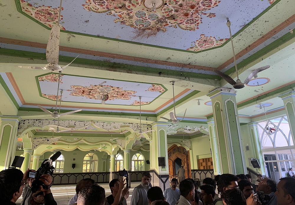 Journalists take photos of a blood stains from the top of a mosque following a suicide bombers attack in the city of Kandahar, southwest Afghanistan, Friday, Oct. 15, 2021. Suicide bombers attacked a Shiite mosque in southern Afghanistan that was packed with worshippers attending Friday prayers, killing several people and wounding others, according to a hospital official and a witness. (AP Photo/Sidiqullah Khan)