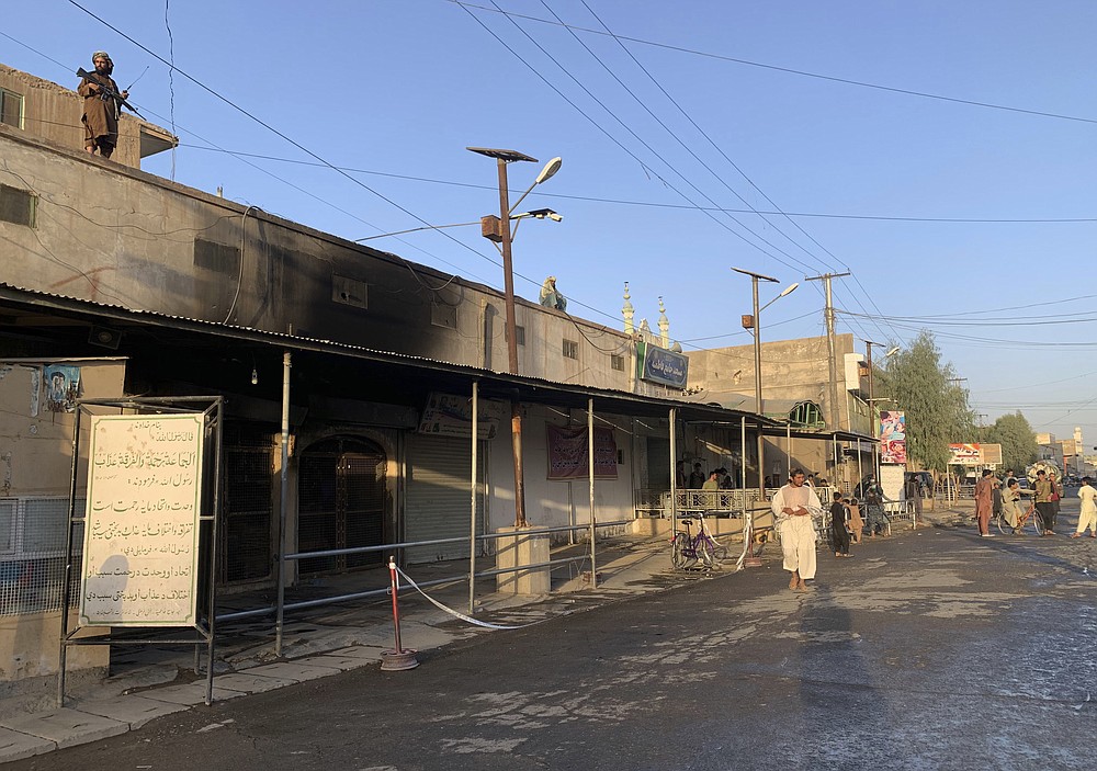 People inspect the outside of a mosque following a suicide bombers attack in the city of Kandahar, southwest Afghanistan, Friday, Oct. 15, 2021. Suicide bombers attacked a Shiite mosque in southern Afghanistan that was packed with worshippers attending Friday prayers, killing several people and wounding others, according to a hospital official and a witness. (AP Photo/Sidiqullah Khan)