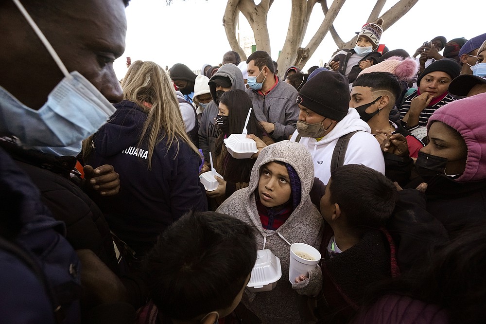 FILE — In this Feb. 19, 2021 file photo asylum seekers receive food as they wait for news of policy changes at the border, in Tijuana, Mexico. The Biden administration outlined a plan to reinstate a border policy that made asylum-seekers wait in Mexico for hearings in U.S. immigration court. Details were disclosed in a court filing after a federal judge in Texas ordered that the policy by resumed "in good faith," having started under President Donald Trump and sending about 70,000 people back to Mexico until Biden abruptly ended because he felt it was inhumane. (AP Photo/Gregory Bull, File)