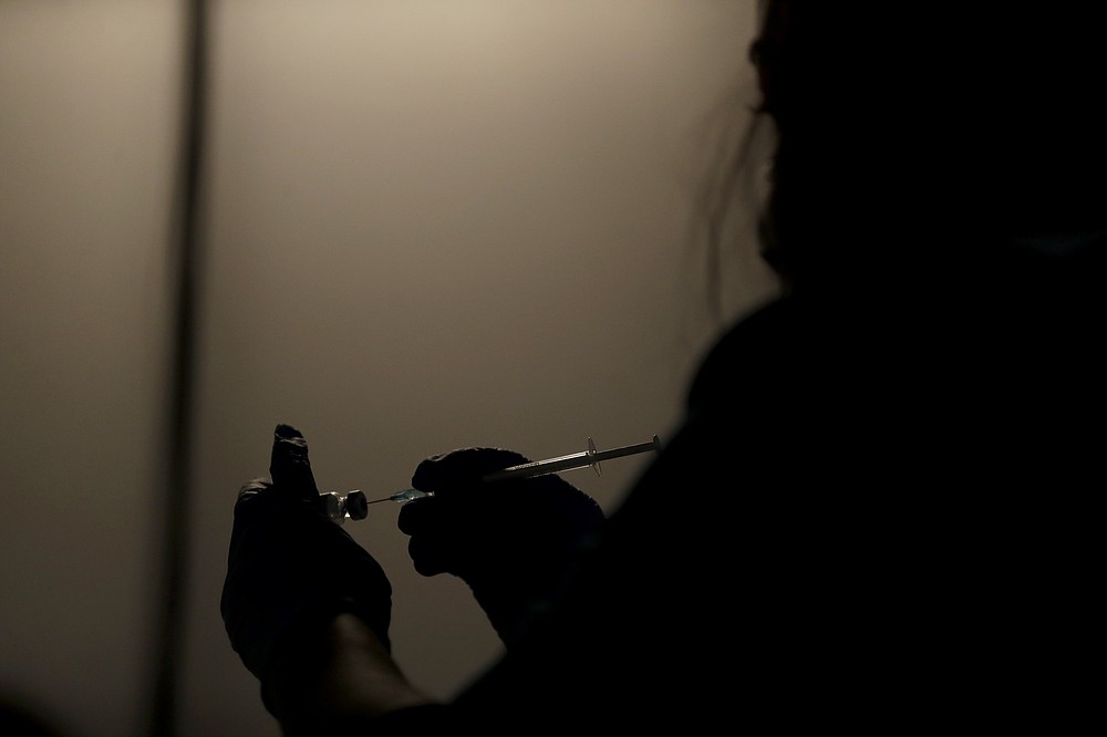 FILE - In this May 1, 2021, file photo, a volunteer vaccinator prepares to administer a dose of the Pfizer coronavirus vaccine at a vaccine center in Neasden, north London. On Friday, Oct. 15, The Associated Press reported on stories circulating online incorrectly claiming a video shows people dropping “dead” outside a COVID-19 vaccination clinic in London after receiving a shot. (AP Photo/Matt Dunham, File)